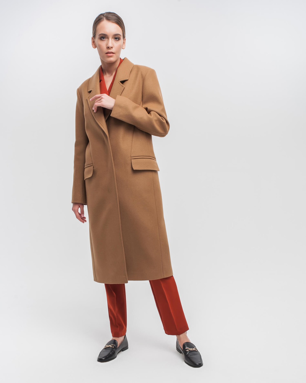 Однобортное пальто приталенного силуэта с клапанами на карманах и потайной застежкой на пуговицы. Линия отстрочек на лацканах и четкие линии плеч формируют современный силуэт.