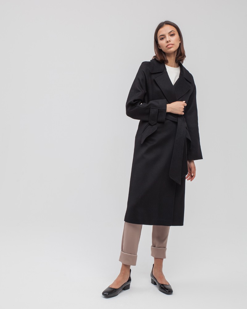 Пальто-халат с клапанами на карманах, рукавом реглан. Дополнено декоративными отстрочками и воротником-стойка с фигурным вырезом. Данная модель красиво подчеркивает женственные формы за счет пояса.