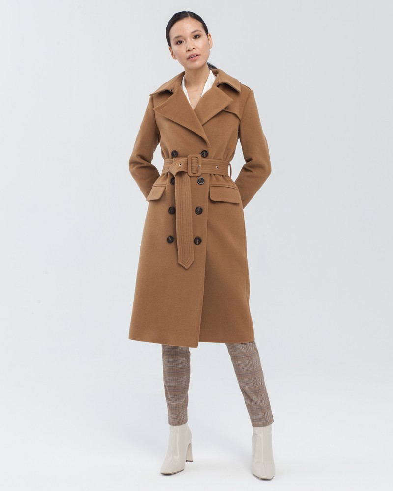 Двубортное пальто-тренч классической посадки с застежкой на пуговицы. Дополнено простроченным поясом с обтяжной пряжкой в тон изделия и отлетной кокеткой на спинке. Застежка на вороте позволяет запахнуть ворот и защищает от сильного ветра.