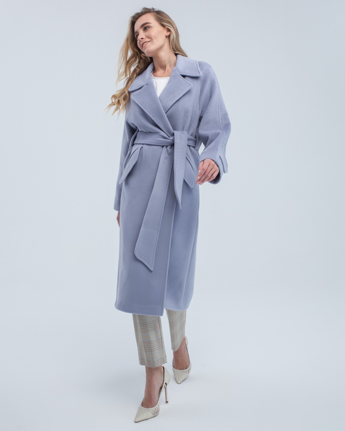 Пальто-халат длины миди с клапанами на карманах, рукавом реглан. Дополнено декоративными отстрочками и воротником-стойка с фигурным вырезом. Данная модель красиво подчеркивает женственные формы за счет пояса.

На модели размер XS