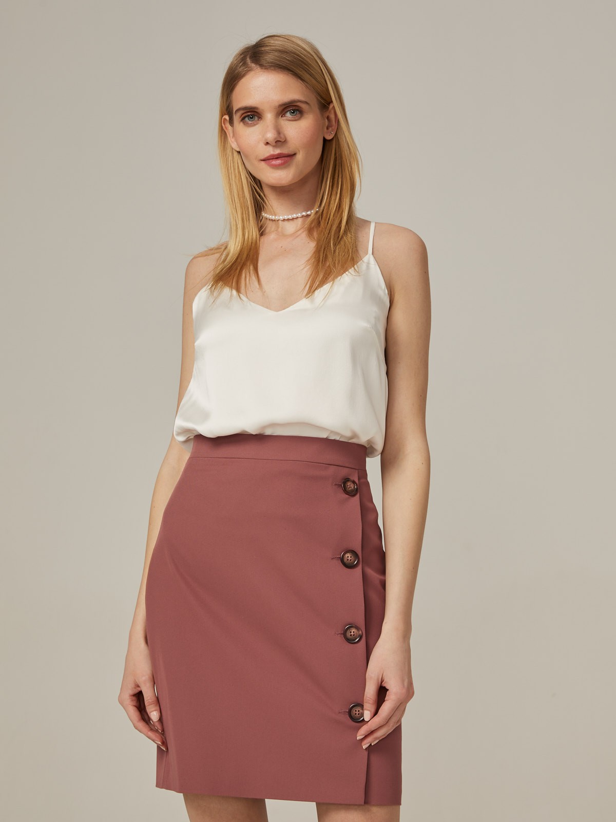 Прямая юбка длины мини на высокой посадке. модель дополнена 4 декоративными пуговицами по левому боку. Верхний срез обработан отрезным поясом.
Цветомодели кэмел и терракотовый на 35% выполнены из переработанного пластика.

На модели размер XS

