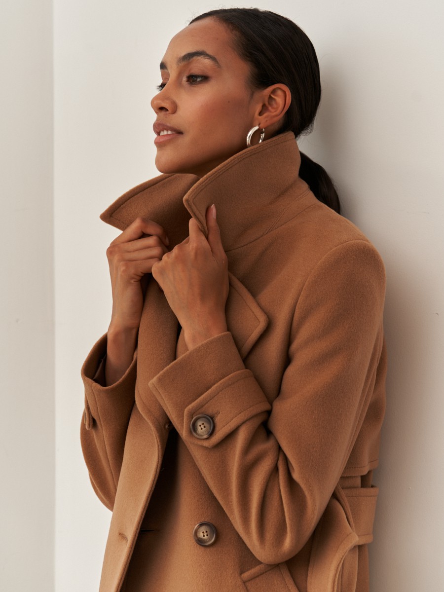 Двубортное пальто-тренчс кокеткой по спинке, широким поясом на пуговицах и шлицей сзади.
Рукава декорированы патами на пуговицах. Классический крой в сочетании с элементами стиля милитари - отличная альтернатива минимализму.

На модели размер XS