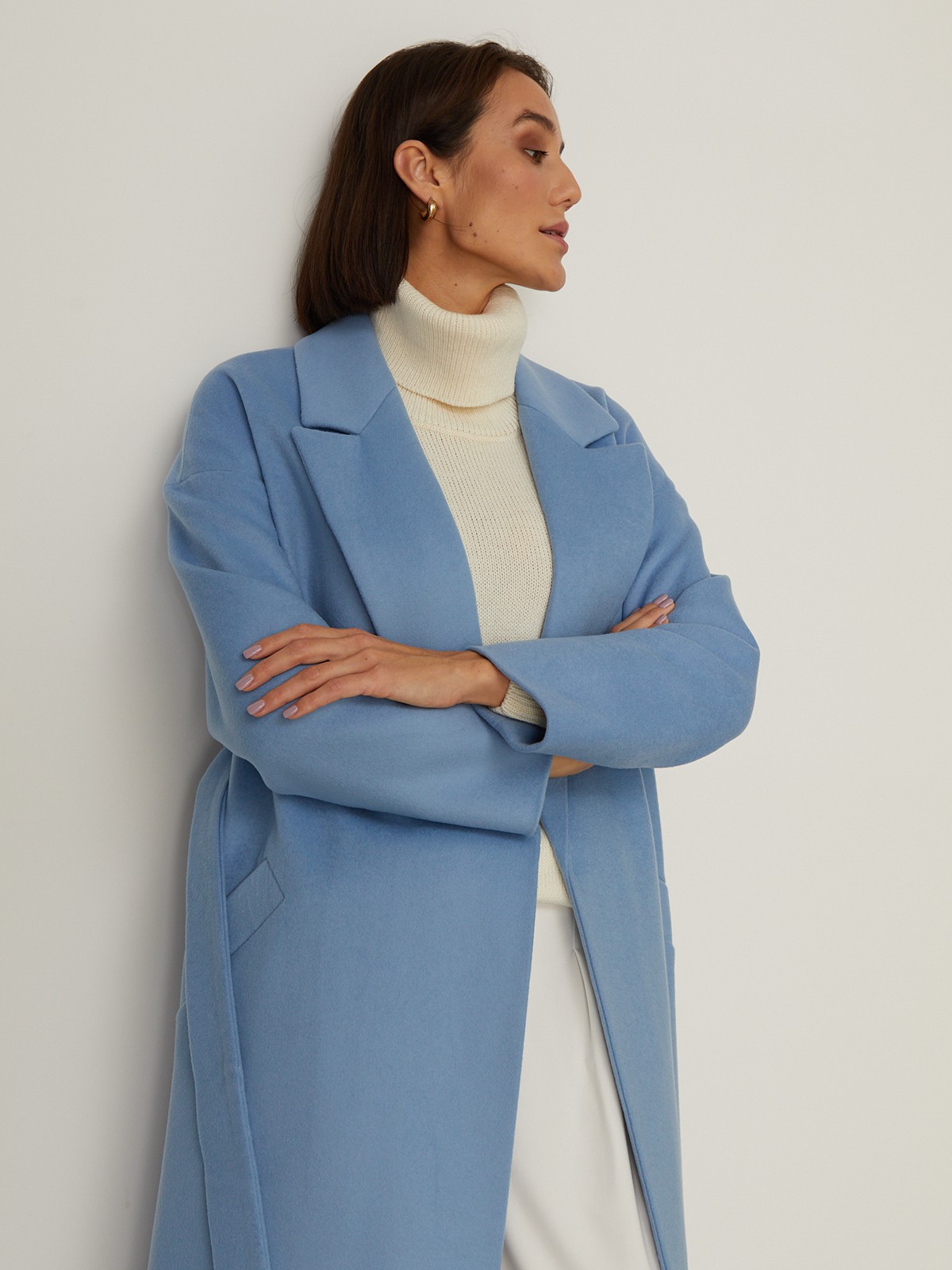 Пальто-халат из плотной шерсти. Модель прямого силуэтас английским воротником.Пальто дополнено двумя вместительными карманами,без застежки, с поясом из основного материала.

На модели размер XS