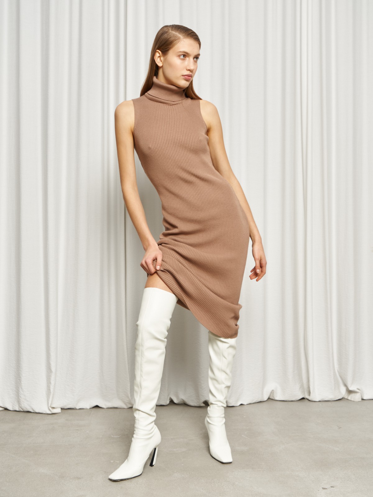 Платье без рукавов из вязаного трикотажа оформлено высокой горловиной-стойкой. Посадка по фигуре.

На модели размер XS