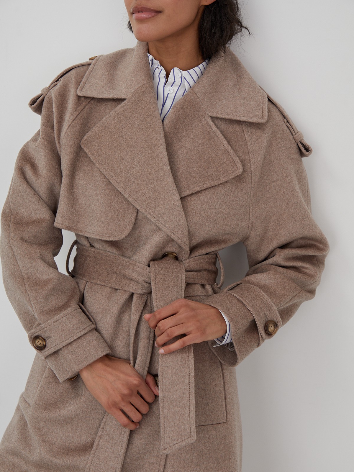 Двубортное пальто-тренч свободного кроя с застежкой на пуговицы. Дополнено поясом, пряжкой на манжетах и погонами в тон изделия. Модный силуэт оверсайз позволяет создавать дерзкие образы в стиле80-х гг.

На модели размер XS