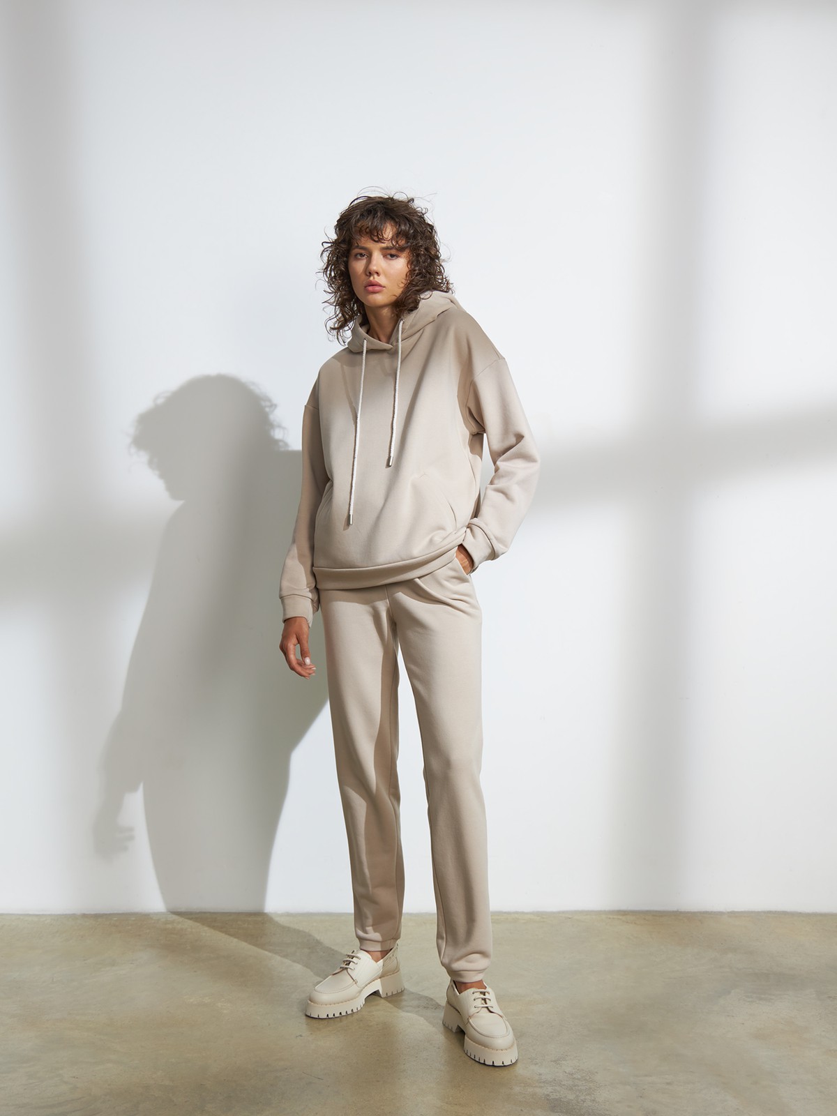 Брюки свободного спортивного силуэта. Модель дополнена манжетами из основной ткани по низу изделия и карманами по боковым швам. На поясе у брюк пояс, регулируемый завязками. Дополните свой образ толстовкой в тон изделия.

На модели размер XS