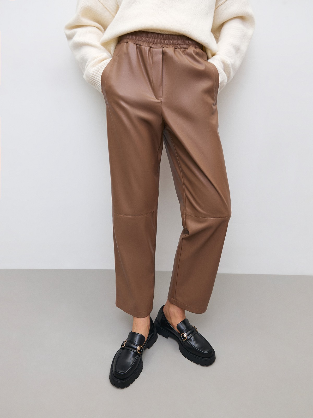 


Широкие брюки из экокожи. Посадка на резинке, благодаря чему вы можете регулировать линию талии по желанию. Шов в районе колена для объема. Два кармана, куда можно положить телефон и ключи. Мы предлагаем сочетать брюки с рубашкой из экокожи или создать контраст фактур.

На модели размер XS