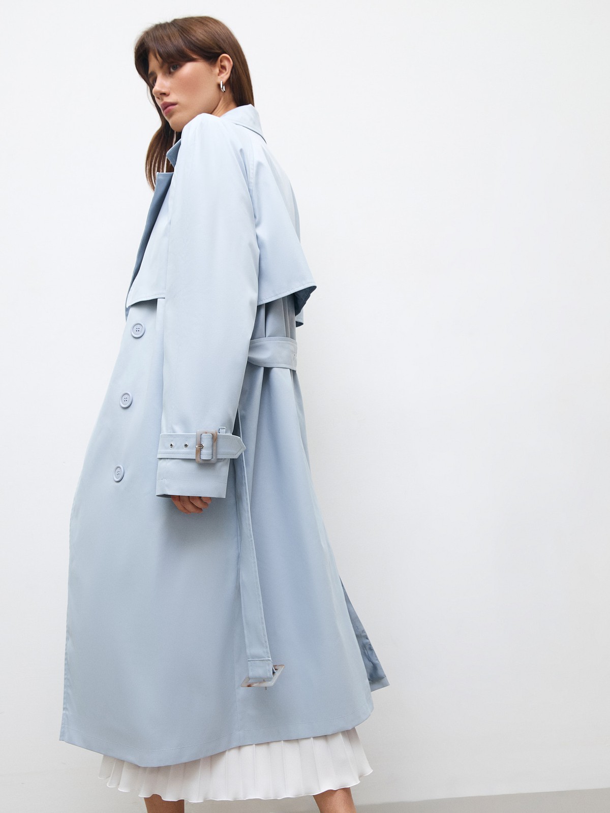 Тренч, цвет: серо-голубой Allweneed Плащдвубортного кроя с застежкой на крупные однотонные пуговицы. Отлетная кокетка, А-силуэт и длинный пояс на талии добавляют образу легкости, а цветовая гамма создает поистине весеннее настроение.