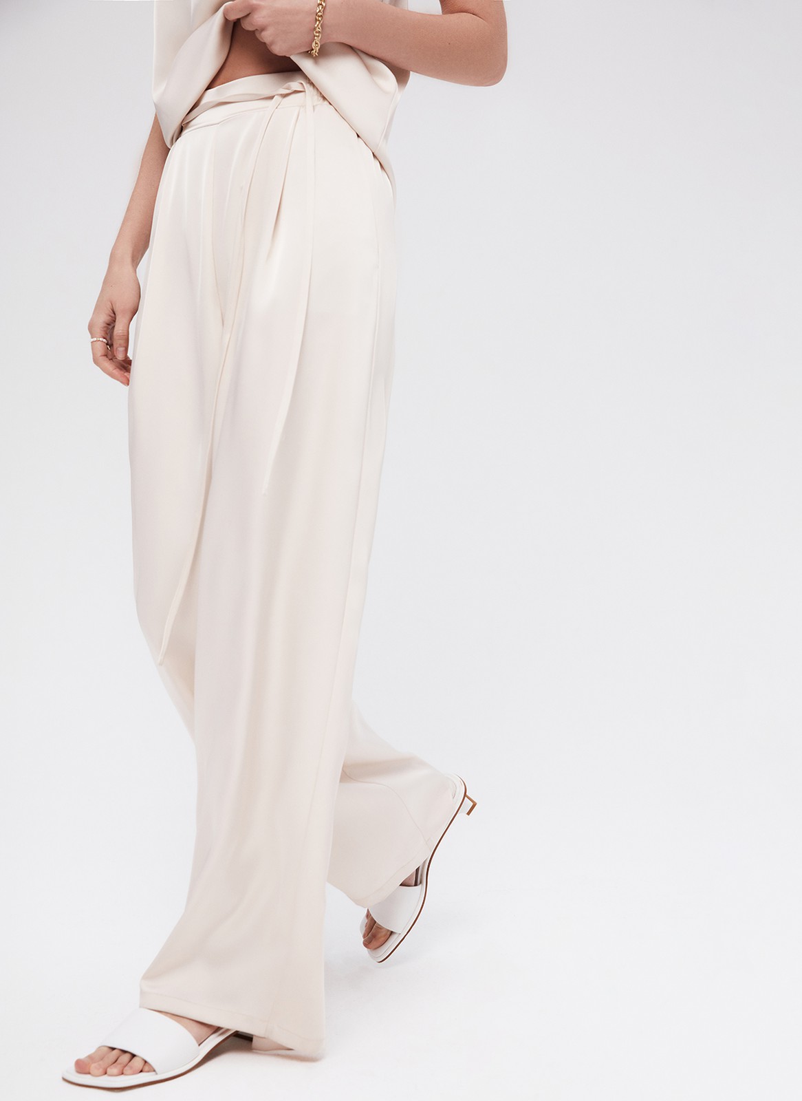 Брюки палаццо, цвет: бежевый Allweneed
Легкие брюки свободного кроя из ткани атласного переплетения. Ткань струится и переливается при ходьбе, но неприхотлива в уходе. Широкий пояс с резинкой, декоративный шнурок на поясе, глубокие складки на передней части брюк. Удобные карманы. Вы можете добавить по желанию изящные босоножки или удобные кеды, футболку oversize или топ с открытой спиной. Можно составить комплект с рубашкой и топом из нашей коллекции.
На модели размер XS