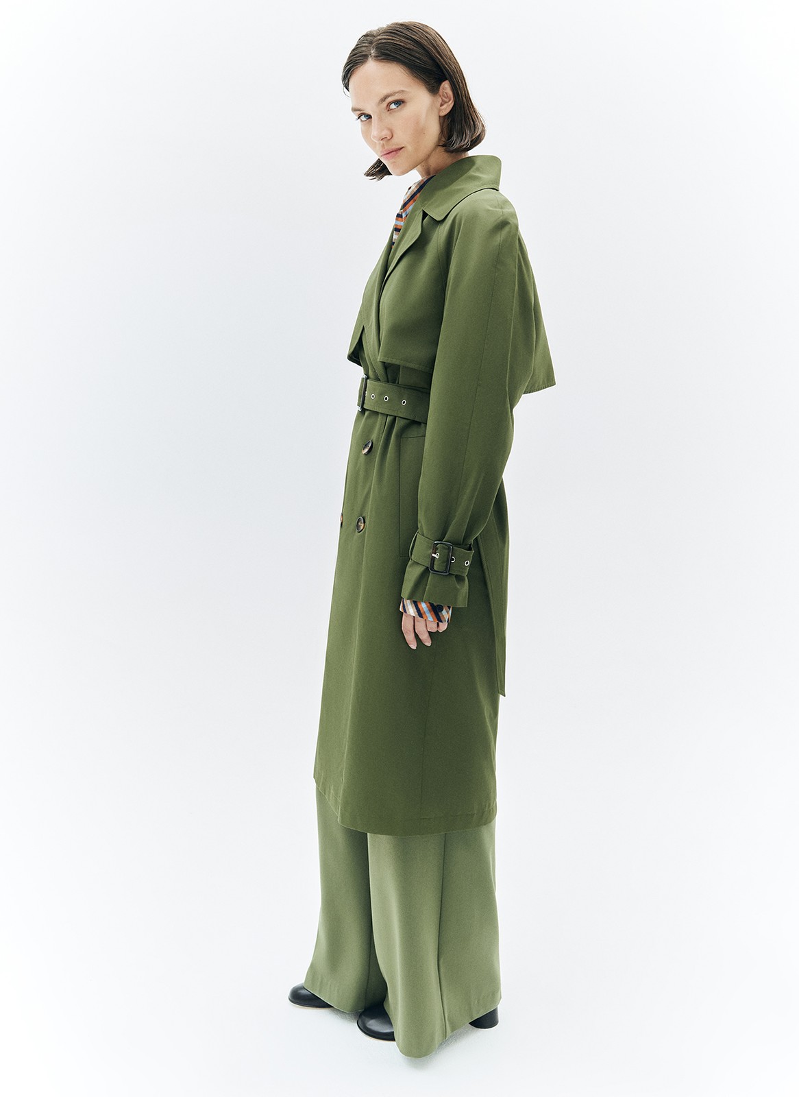 Тренч, цвет: хаки Allweneed Плащ двубортного кроя с застёжкой на крупные контрастные пуговицы. Мы сохранили все детали классической модели: отлетную кокетку, А-силуэт, манжеты для фиксации рукава и длинный пояс на талии. Мы любим плащ за то, что с ним можно составлять женственные и универсальные повседневные образы.