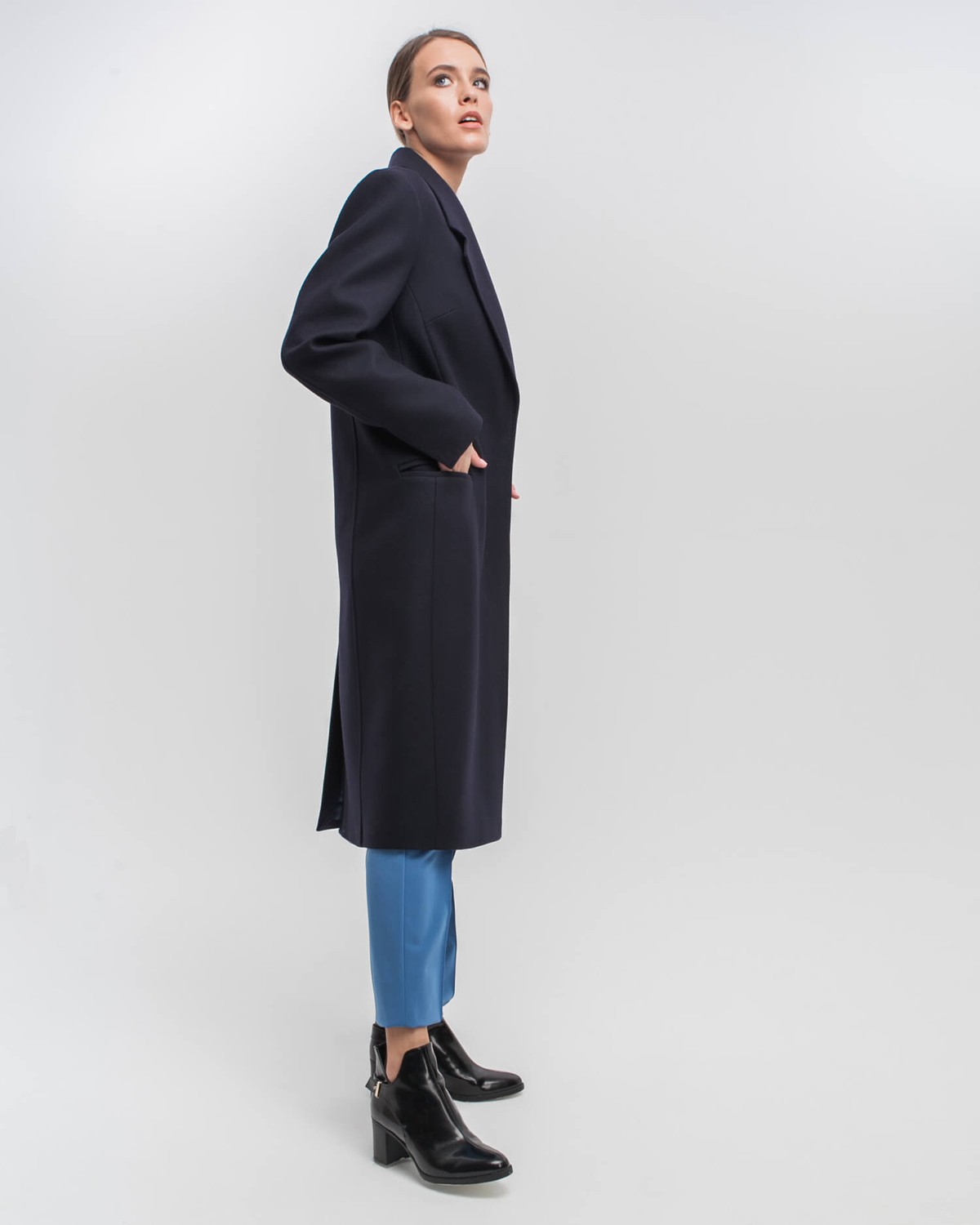 Однобортное пальто приталенного силуэта с клапанами на карманах и потайной застежкой на пуговицы. Линия отстрочек на лацканах и четкие линии плеч формируют современный силуэт.