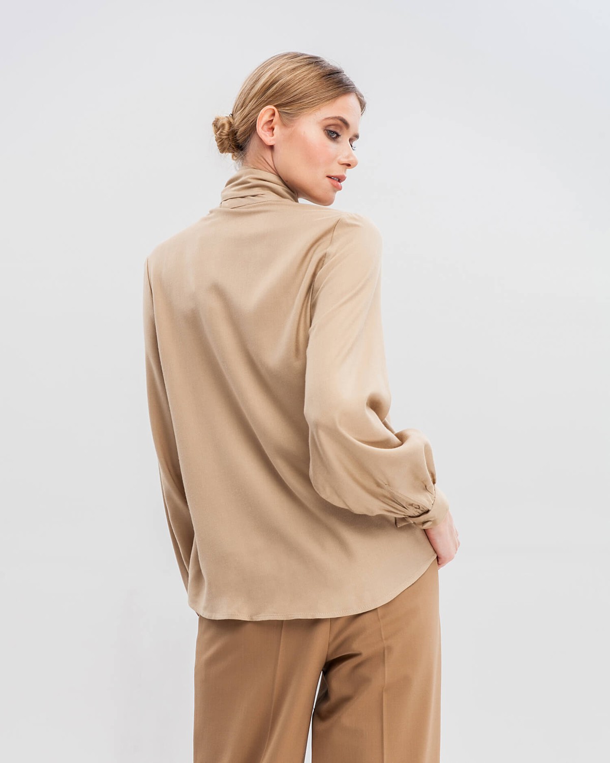 Блуза с широкими рукавами, узкими манжетами, драпировкой и бантом на груди добавит женственности любому деловому образу.
