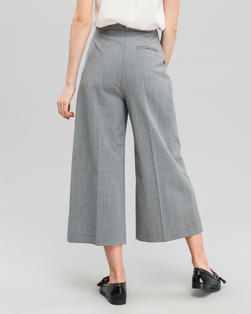 Широкие брюки-кюлоты с простроченной стрелкой и посадкой на талии. Брюки дополнены карманами, застежкой на пуговицу и молнию. За счет силуэта трапеции, который создают кюлоты, можно собирать женственные и утонченные образы.