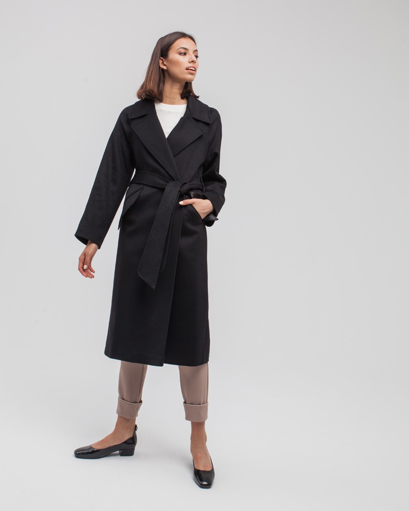 Пальто-халат с клапанами на карманах, рукавом реглан. Дополнено декоративными отстрочками и воротником-стойка с фигурным вырезом. Данная модель красиво подчеркивает женственные формы за счет пояса.