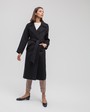 Пальто-халат с клапанами на карманах, рукавом реглан. Дополнено декоративными отстрочками и воротником-стойка с фигурным вырезом. Данная модель красиво подчеркивает женственные формы за счет пояса.