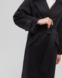 Пальто-халат с клапанами на карманах, рукавом реглан. Дополнено декоративными отстрочками и воротником-стойка с фигурным вырезом. Данная модель красиво подчеркивает женственные формы за счет пояса.