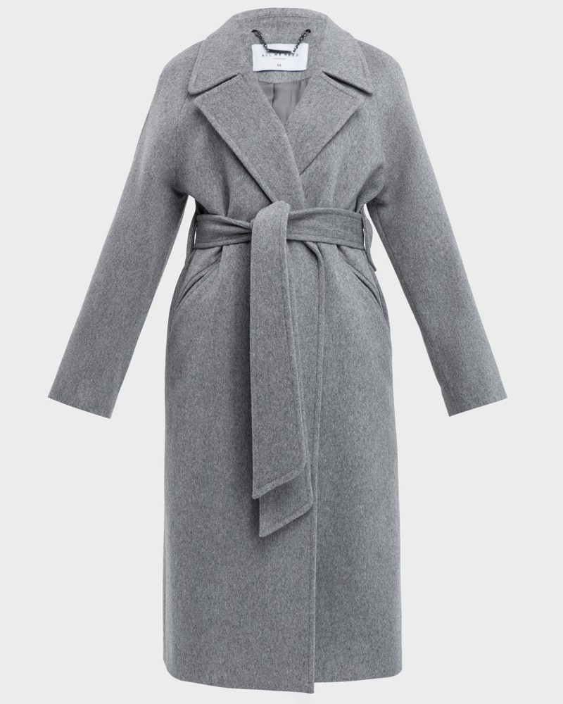 Пальто-халат с клапанами на карманах, рукавом реглан. Дополнено декоративными отстрочками и воротником-стойка с фигурным вырезом. Данная модель красиво подчеркивает женственные формы за счет пояса.

На модели размер XS