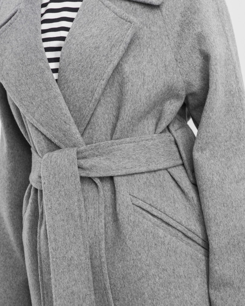 Пальто-халат с клапанами на карманах, рукавом реглан. Дополнено декоративными отстрочками и воротником-стойка с фигурным вырезом. Данная модель красиво подчеркивает женственные формы за счет пояса.

На модели размер XS