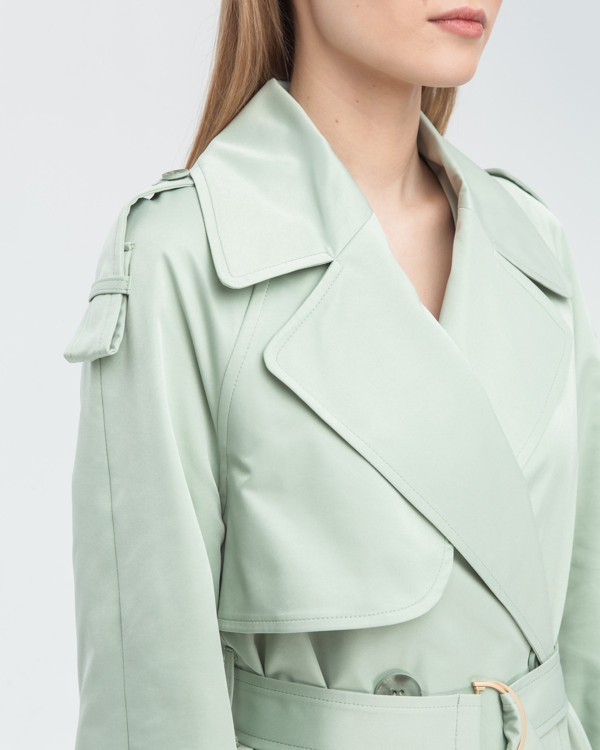 Тренч классической посадки с рукавом реглан. Дополнен погонами, патами на рукавах и поясом в тон изделия с металлической пряжкой. Выполнен из плащевой ткани с добавалением хлопка, на подкладке. Защитит от ветра весенними вечерами.