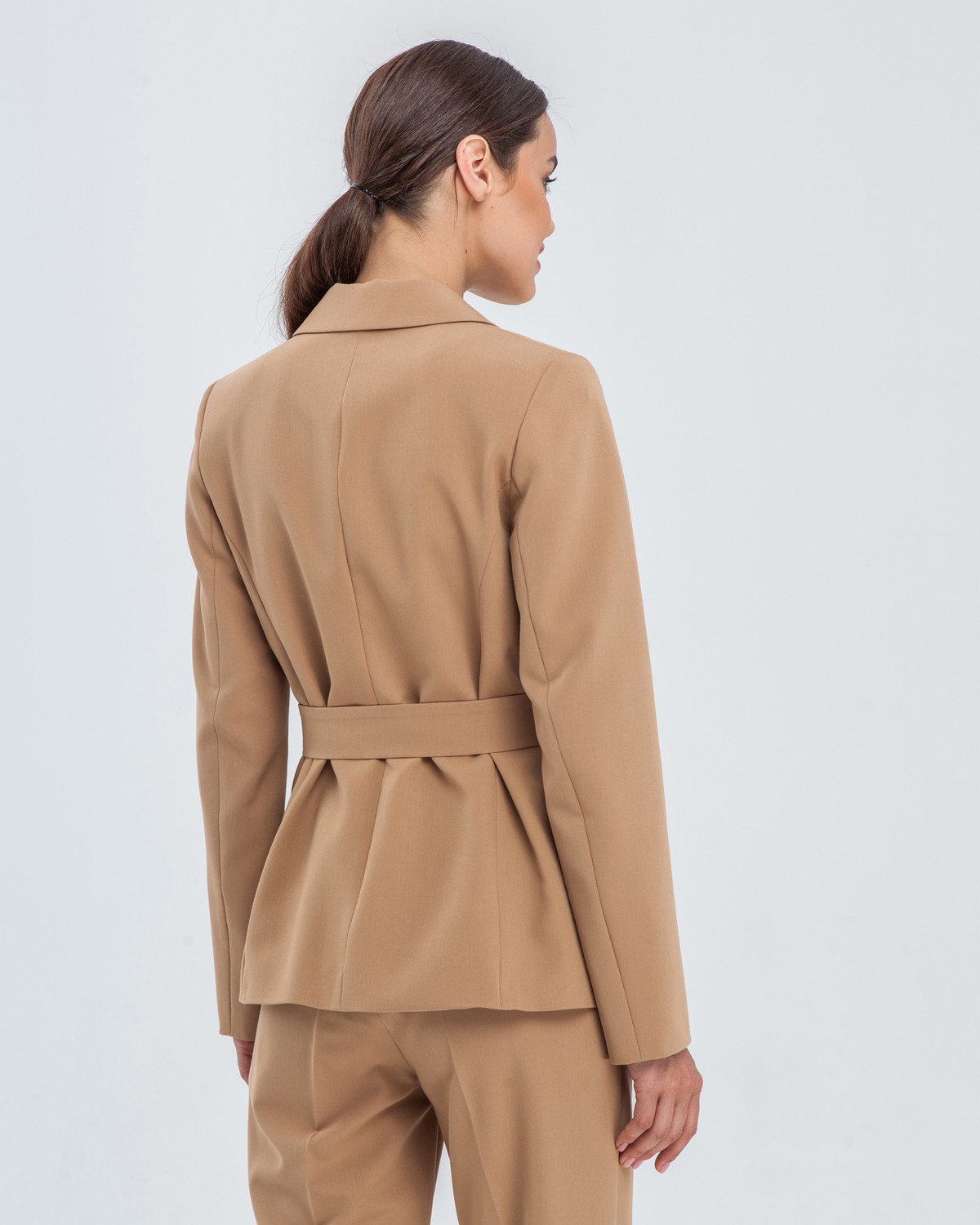 Слегка приталенный однобортный жакет с застежкой на две пуговицы и клапанами на карманах. Дополнен широким поясом с обтяжной пряжкой в тон изделия и обтяжными пуговицами. Широкий пояс подчеркнет тонкую талию и сформирует силуэт песочные часы