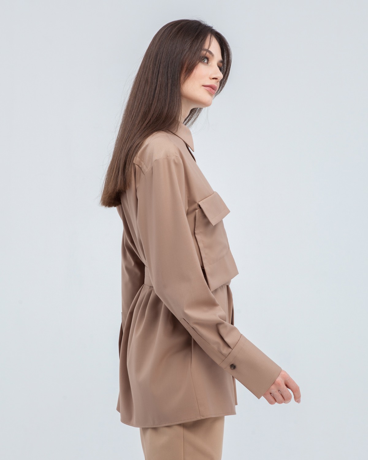 Акцентная удлиненная рубашка с объемным накладным карманом и плиссировкой по левому боку. Дополнена поясом на пуговицах в тон изделия. Модель позволяет носить ее как с поясом, так и без. Идеальный вариант для создания уникального делового или повседневного образа.

На модели размер XS