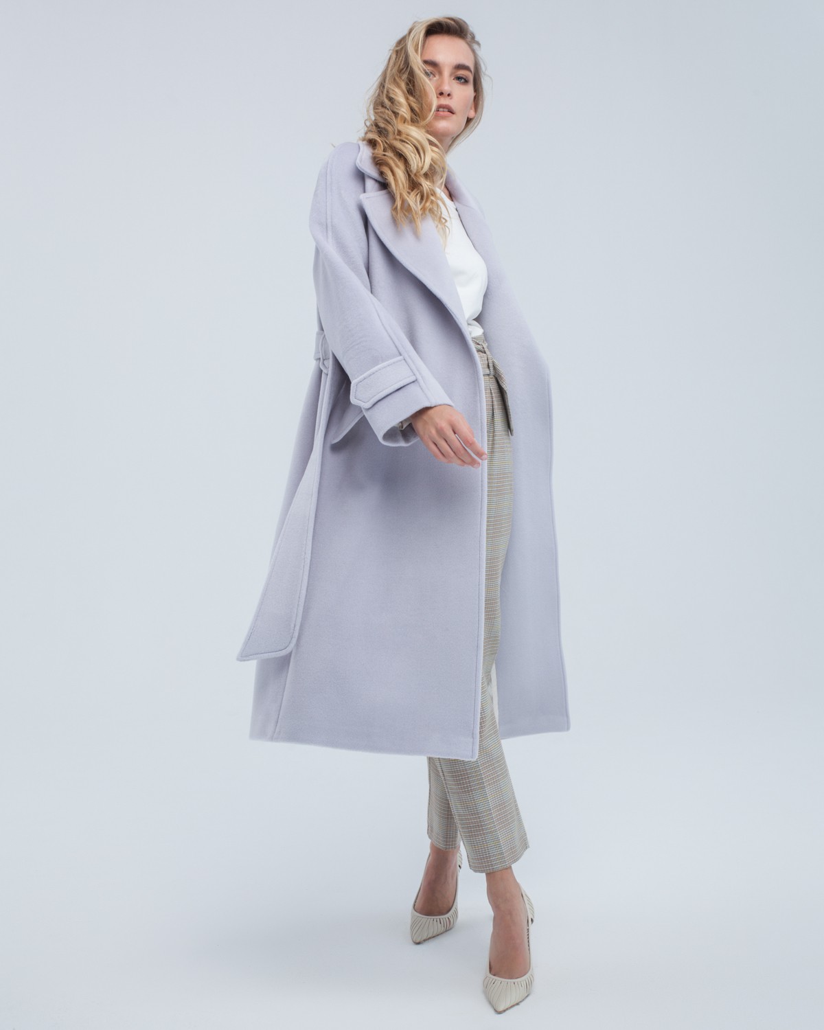 Пальто-халат длины миди с клапанами на карманах, рукавом реглан. Дополнено декоративными отстрочками и воротником-стойка с фигурным вырезом. Данная модель красиво подчеркивает женственные формы за счет пояса.

На модели размер XS