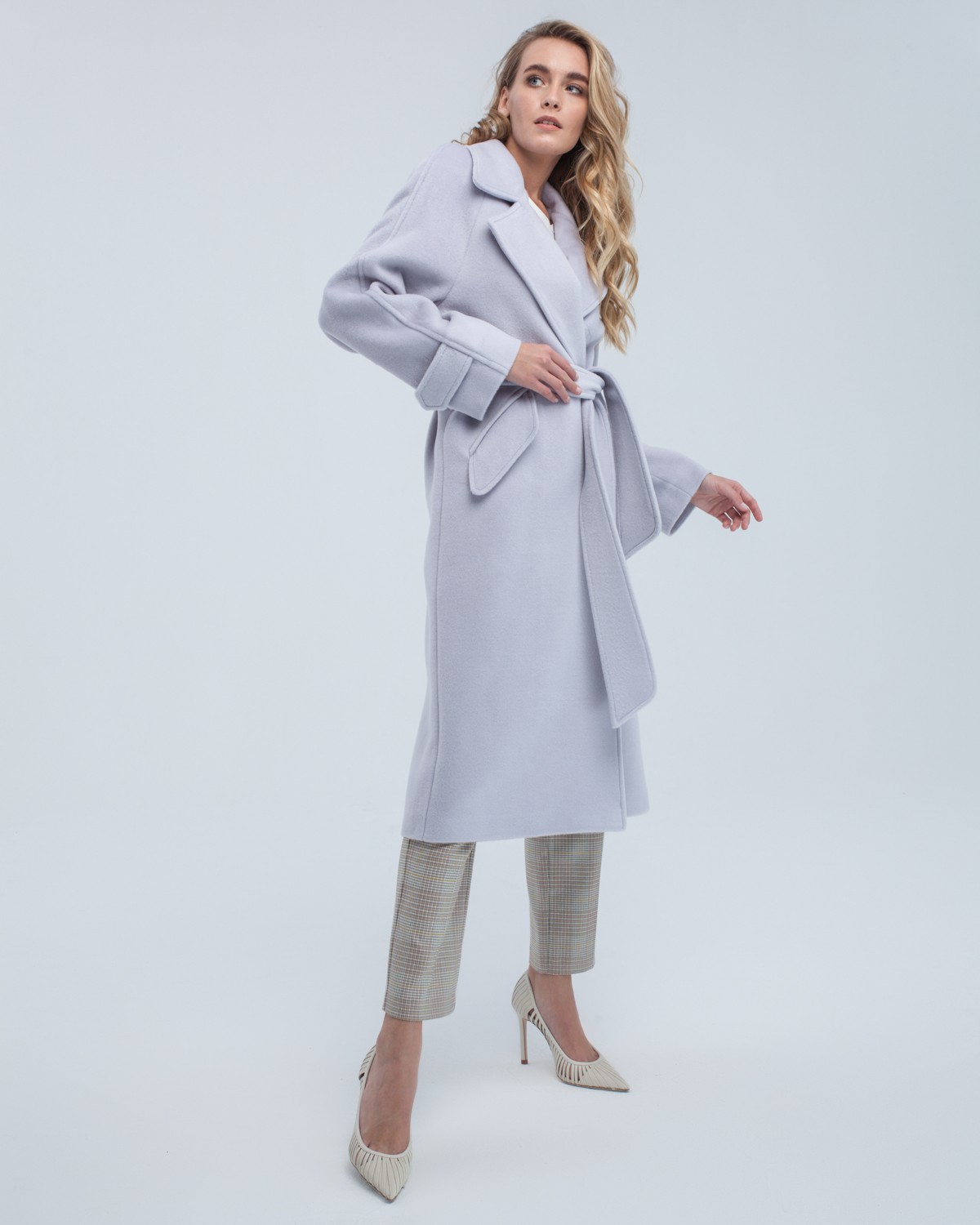 Пальто-халат длины миди с клапанами на карманах, рукавом реглан. Дополнено декоративными отстрочками и воротником-стойка с фигурным вырезом. Данная модель красиво подчеркивает женственные формы за счет пояса.

На модели размер XS