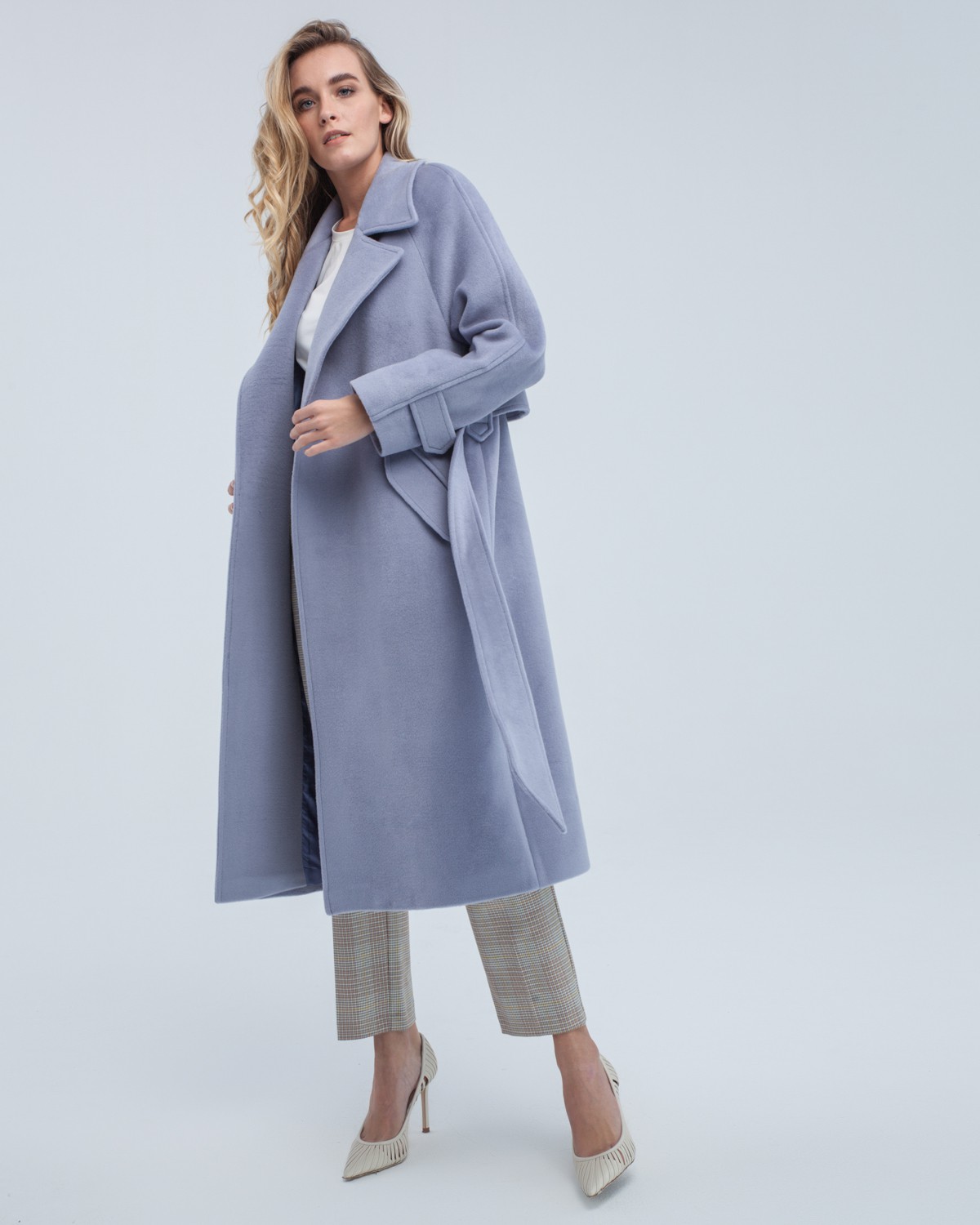 Пальто-халат длины миди с клапанами на карманах, рукавом реглан. Дополнено декоративными отстрочками и воротником-стойка с фигурным вырезом. Данная модель красиво подчеркивает женственные формы за счет пояса.

На модели размер XS