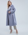 Пальто-халат длины миди с клапанами на карманах, рукавом реглан. Дополнено декоративными отстрочками и воротником-стойка с фигурным вырезом. Данная модель красиво подчеркивает женственные формы за счет пояса.

На модели размер XS