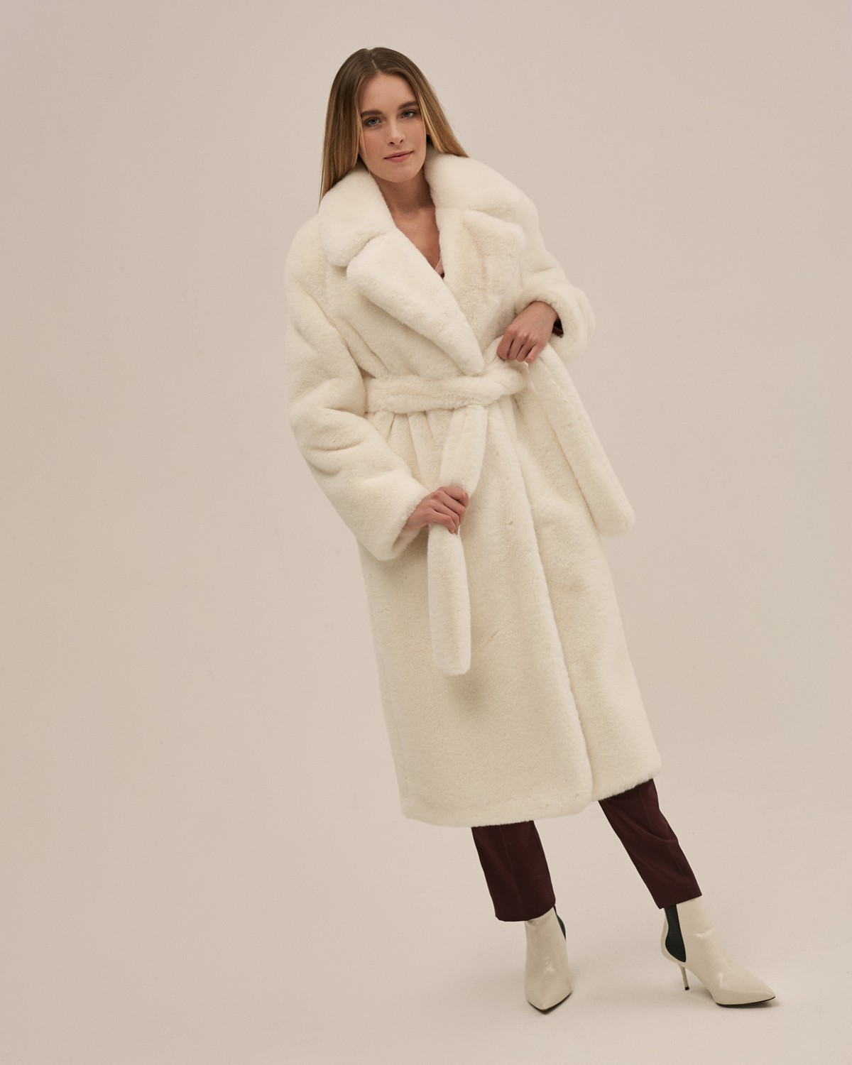 Шуба из искусственного меха прямого кроя длины миди с рукавом реглан и английским воротником. Модель дополнена поясом из основного материала и застегивается на крючки.

Температурный режим: до -10 градусов

На модели размер XS