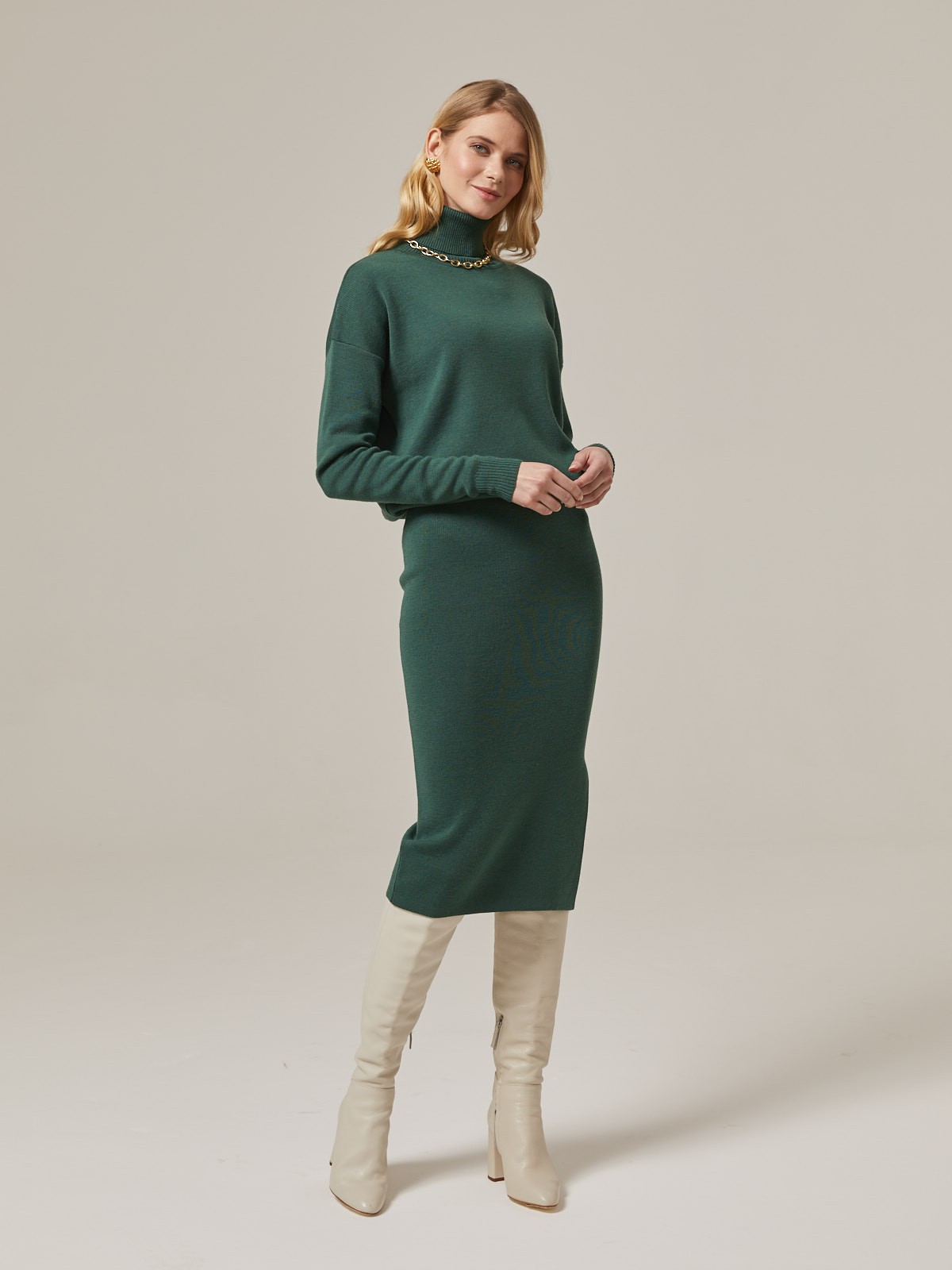 Костюм из вязанного трикотажа, состоящий из юбки с кофтой. Юбка прямая, зауженная к низу. Дополнена разрезом по шву с левой стороны. Кофта прямая со спущенным плечом, дополнена воротником-стойкой.

На модели размер M/L