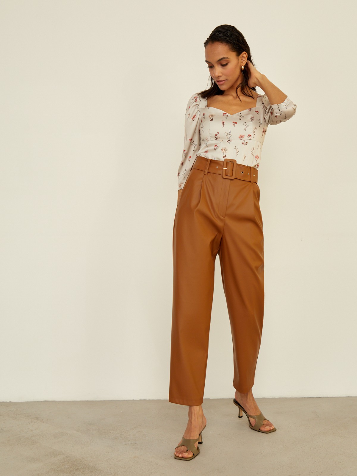 Брюки бананы прямого силуэта слегка зауженные к низу. Модель с высокой посадкой дополнена ремнем с обяжнолй пряжкой. Брюки выполнены из эко-кожи. Дополните образ легкой блузой oversize для создания трендового образа.

На модели размер XS