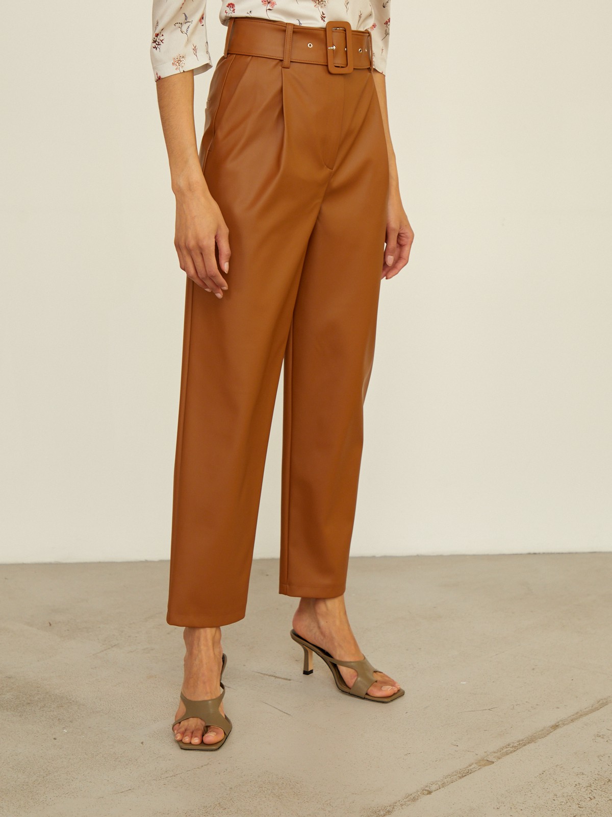 Брюки бананы прямого силуэта слегка зауженные к низу. Модель с высокой посадкой дополнена ремнем с обяжнолй пряжкой. Брюки выполнены из эко-кожи. Дополните образ легкой блузой oversize для создания трендового образа.

На модели размер XS