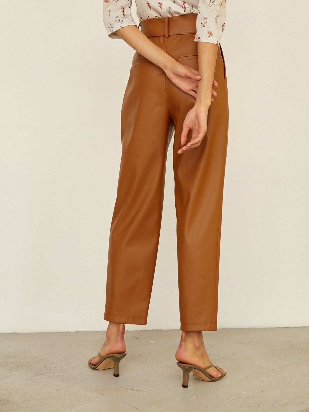 Брюки бананы прямого силуэта слегка зауженные к низу. Модель с высокой посадкой дополнена ремнем с обяжнолй пряжкой. Брюки выполнены из эко-кожи. Дополните образ легкой блузой oversize для создания трендового образа.

На модели размер XS