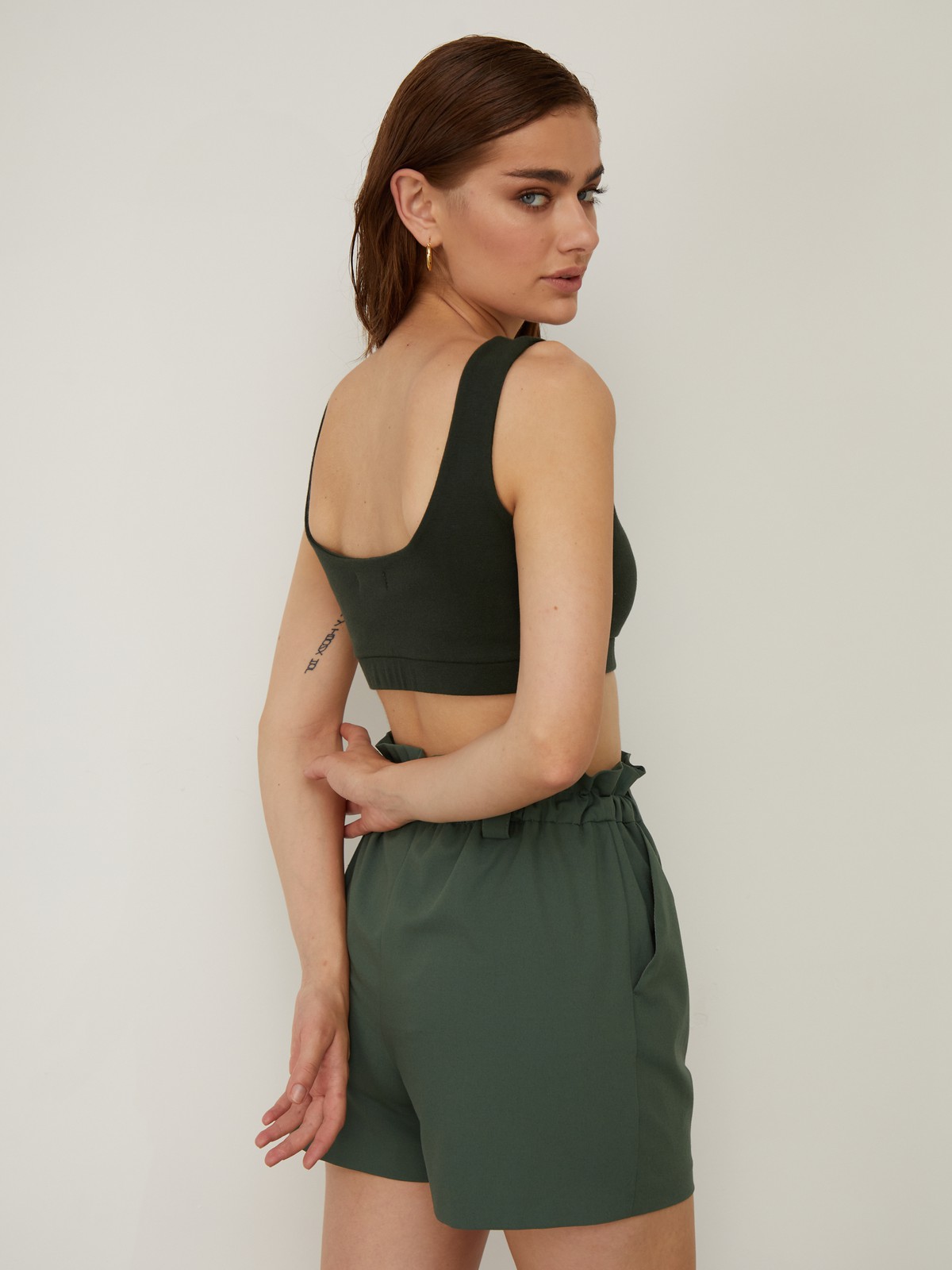 Укороченный топ облегающего кроя выполнен из двухслойной мягкой хлопковой ткани. Ткань топа плотная, что позволит носить его без нижнего белья. Квадратный вырез и широкие бретели подчеркивают плечи и линию декольте.

На модели размер XS
