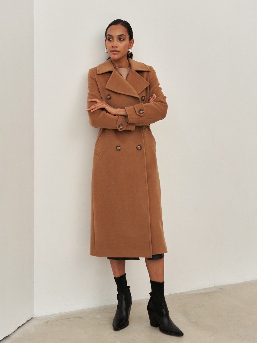 Двубортное пальто-тренчс кокеткой по спинке, широким поясом на пуговицах и шлицей сзади.
Рукава декорированы патами на пуговицах. Классический крой в сочетании с элементами стиля милитари - отличная альтернатива минимализму.

На модели размер XS