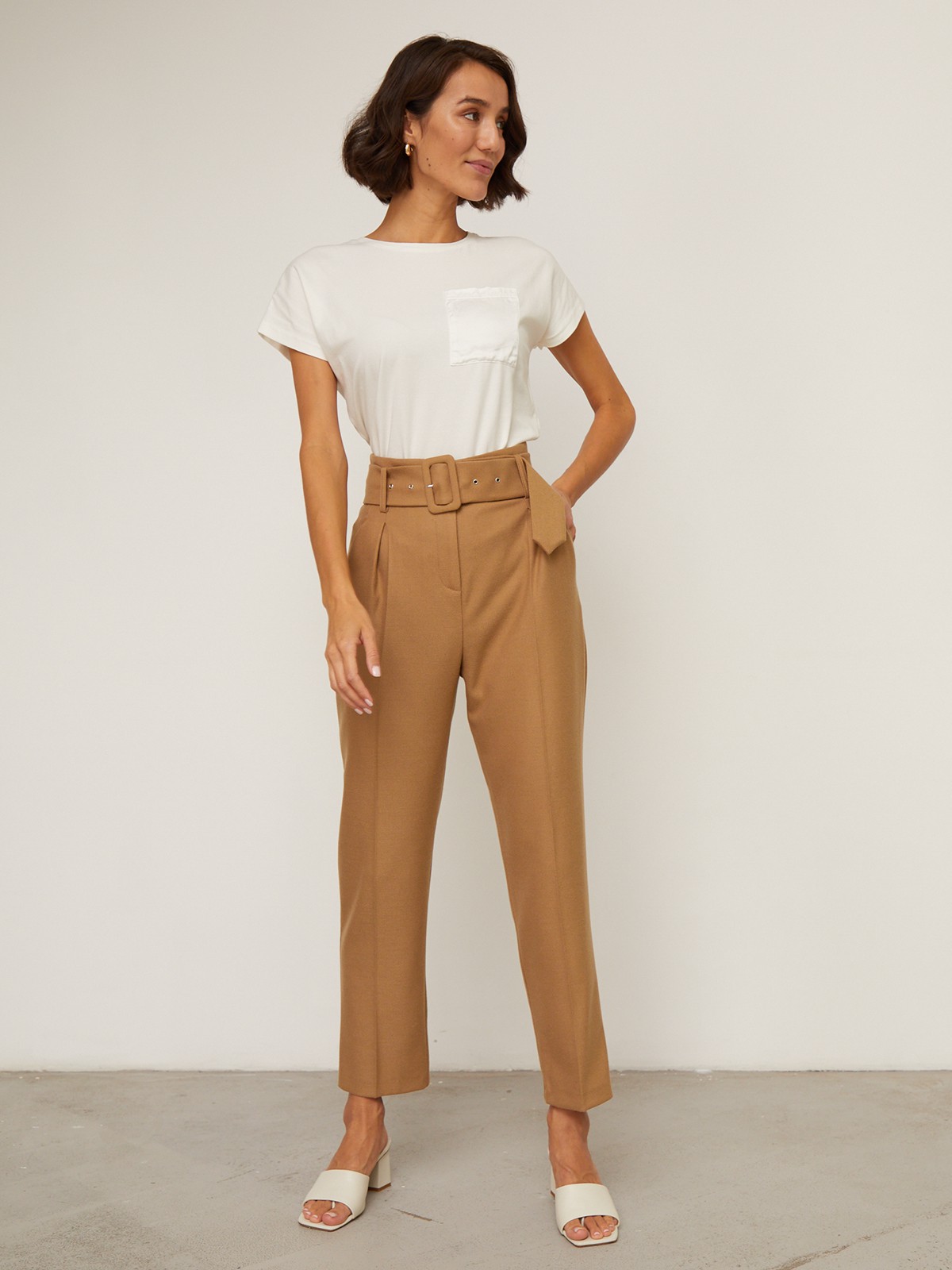 Брюки зауженные с завышенной посадкой, цвет: кэмел Allweneed Слегка зауженные брюки на высокой талии. Дополнены поясом с трендовой в этом сезоне роговой пряжкой. Сочетайте с однотонным жакетом из комплекта для создания изысканного, делового или вечернего образа. Брюки этой модели выпускаются в нашей коллекции уже несколько сезонов подряд, поэтому их посадка безупречна.
На модели размер XS