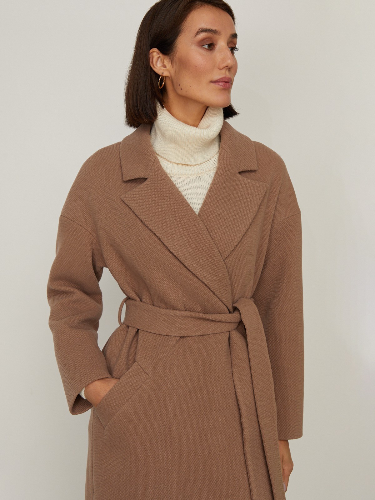 Пальто-халат из плотной шерсти. Модель прямого силуэтас английским воротником.Пальто дополнено двумя вместительными карманами,без застежки, с поясом из основного материала.

На модели размер XS