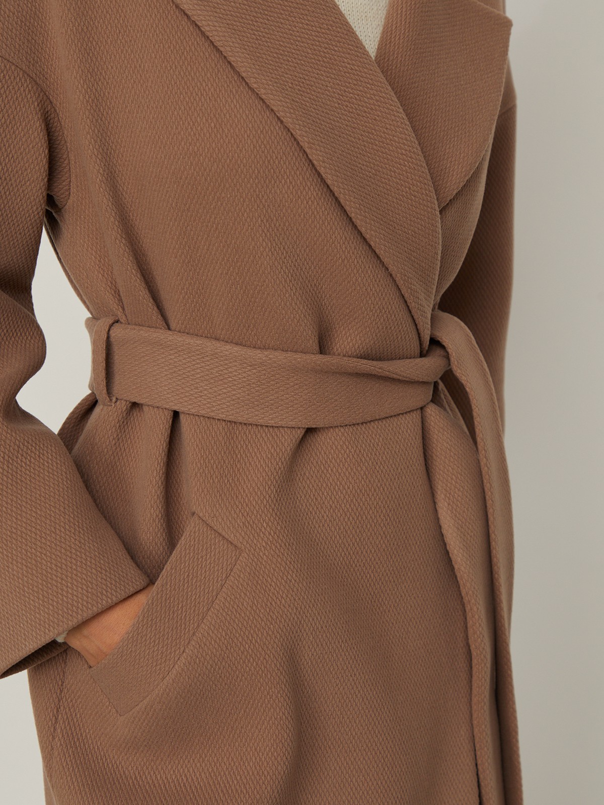 Пальто-халат из плотной шерсти. Модель прямого силуэтас английским воротником.Пальто дополнено двумя вместительными карманами,без застежки, с поясом из основного материала.

На модели размер XS