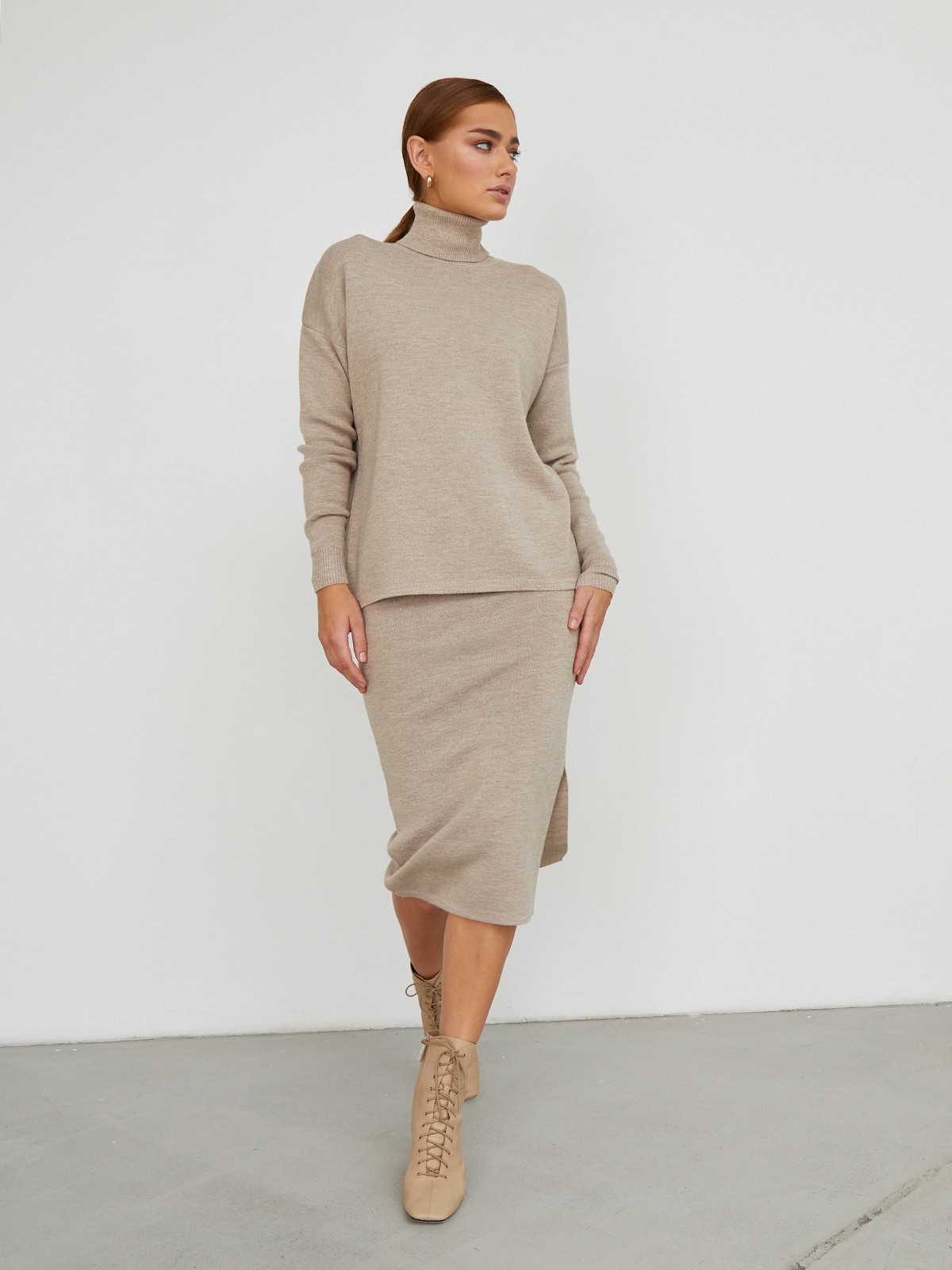 Костюм из вязанного трикотажа, состоящий из юбки с кофтой. Юбка прямая, зауженная к низу. Дополнена разрезом по шву с левой стороны. Кофта прямая со спущенным плечом, дополнена воротником-стойкой.

На модели размер M/L