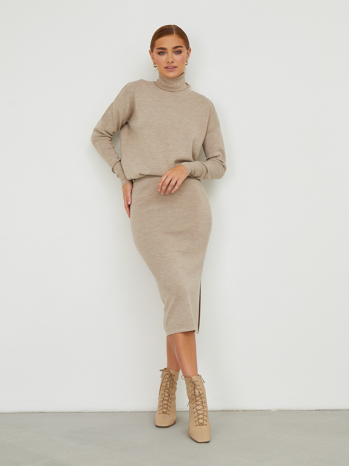 Костюм из вязанного трикотажа, состоящий из юбки с кофтой. Юбка прямая, зауженная к низу. Дополнена разрезом по шву с левой стороны. Кофта прямая со спущенным плечом, дополнена воротником-стойкой.

На модели размер M/L