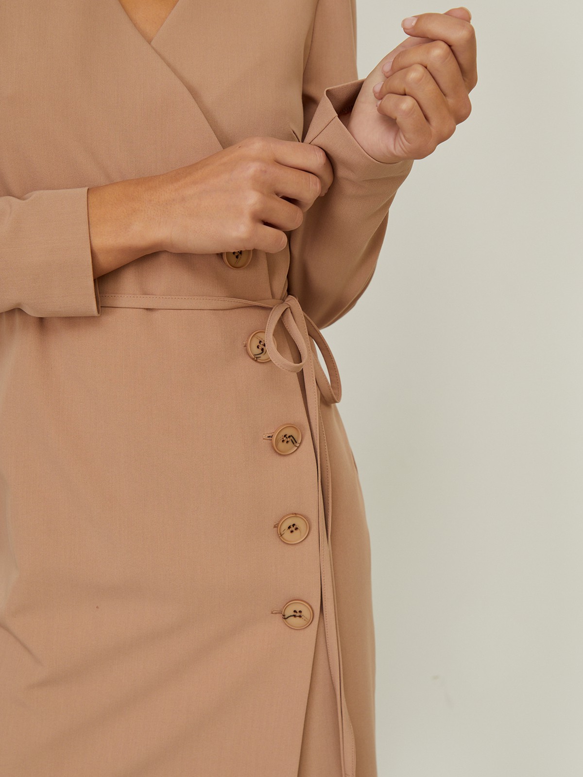 


Платье с драпировкой на запах и V-образным вырезом выполнено из однотонной ткани. Планка-застежка на крупные однотонные пуговицы сбоку. Тонкий пояс на талии.

На модели размер XS