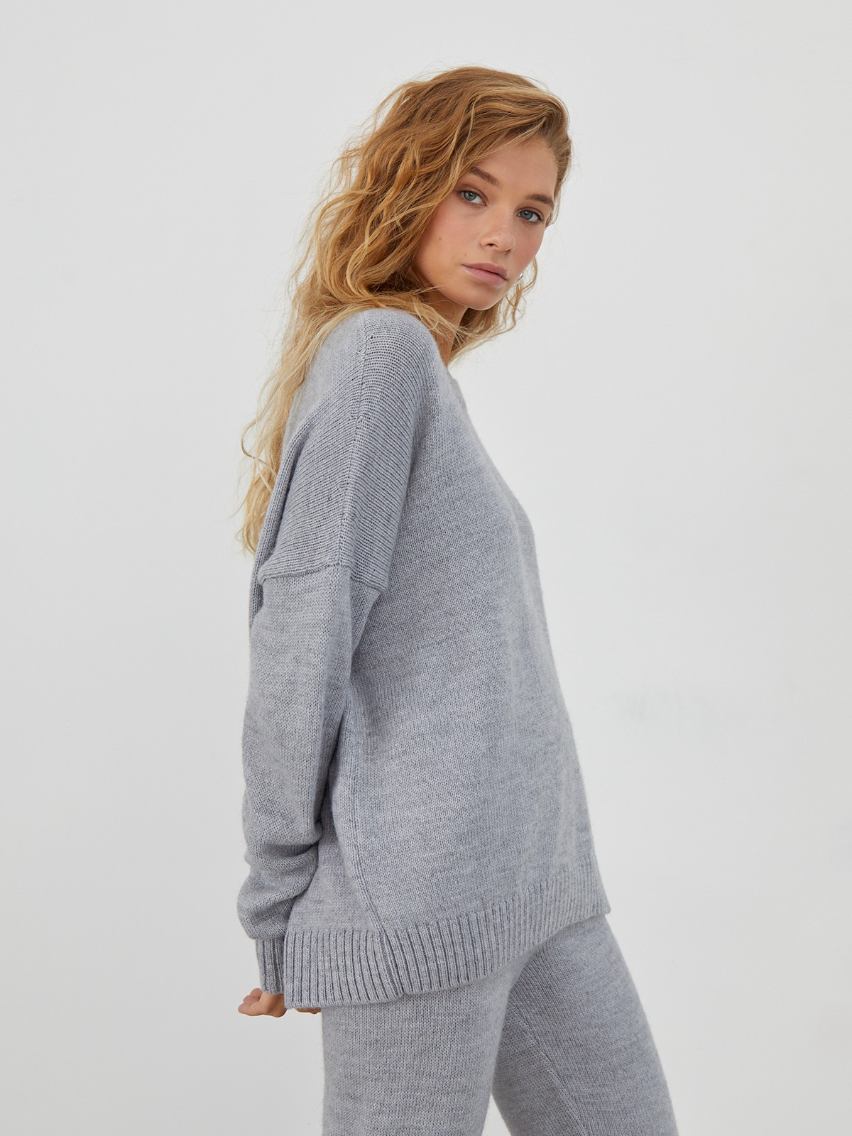 Костюм из вязанного трикотажа, состоящий из кофты и брюк. Кофта свободного силуэта со спущенным плечом. Брюки прямые с резинкой на поясе, зауженные к низу.

На модели размер one size