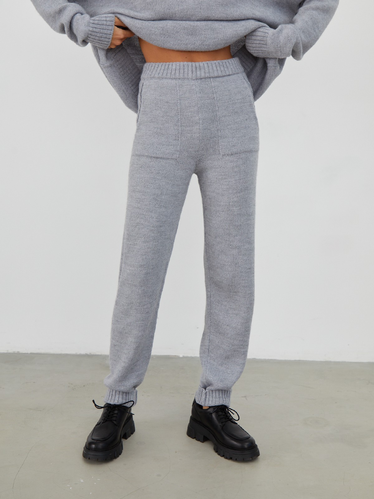 Костюм из вязанного трикотажа, состоящий из кофты и брюк. Кофта свободного силуэта со спущенным плечом. Брюки прямые с резинкой на поясе, зауженные к низу.

На модели размер one size