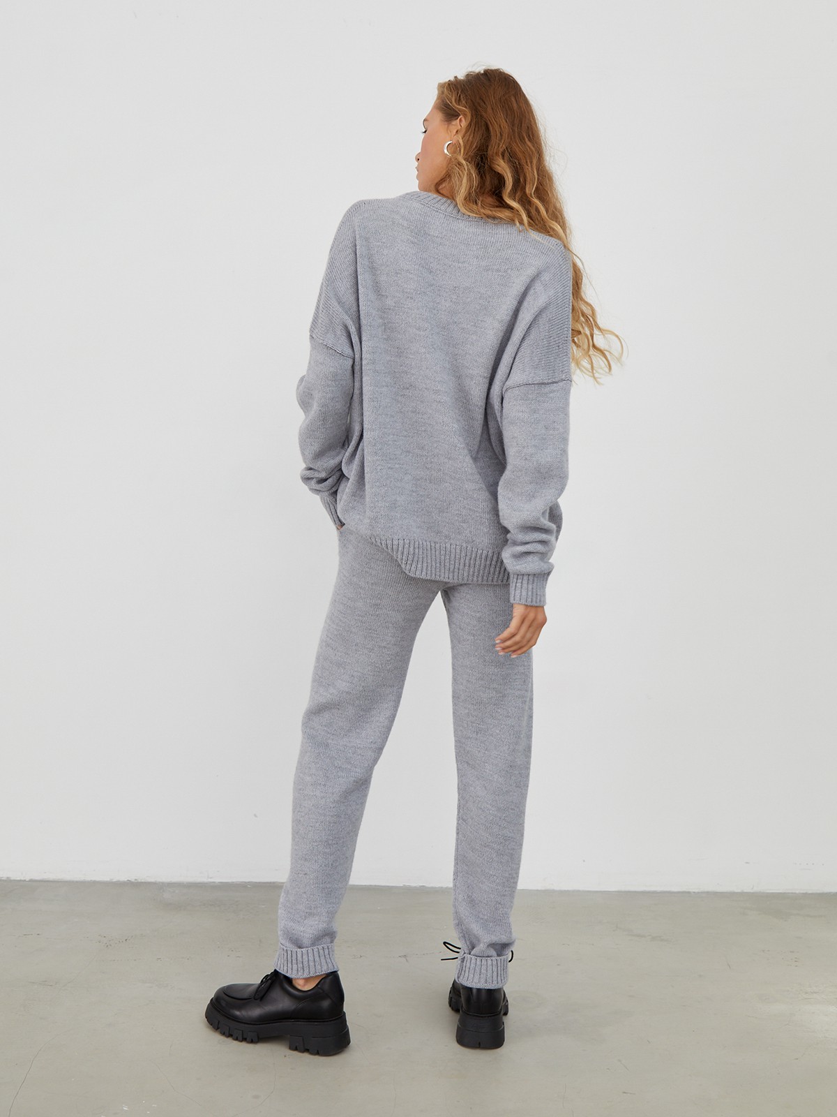 Костюм из вязанного трикотажа, состоящий из кофты и брюк. Кофта свободного силуэта со спущенным плечом. Брюки прямые с резинкой на поясе, зауженные к низу.

На модели размер one size