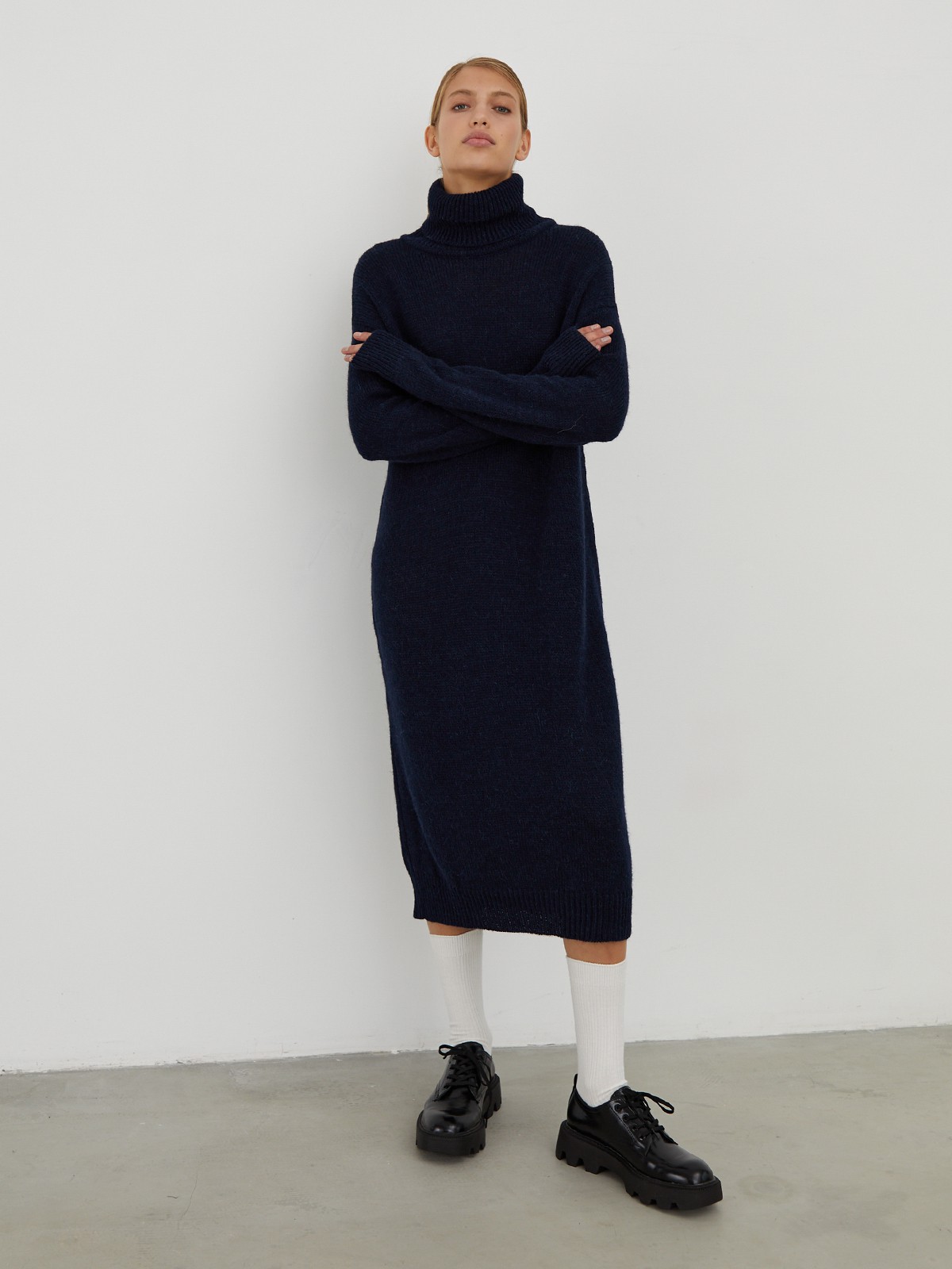 Трикотажное платье длины миди прямого кроя. Дополнено широким высоким воротом. По низу рукава и низу изделия притачан манжет, что создает удобство при ношении платья. Идеальный вариант для прохладных зимнихпрогулок и уютных посиделок с друзьями.