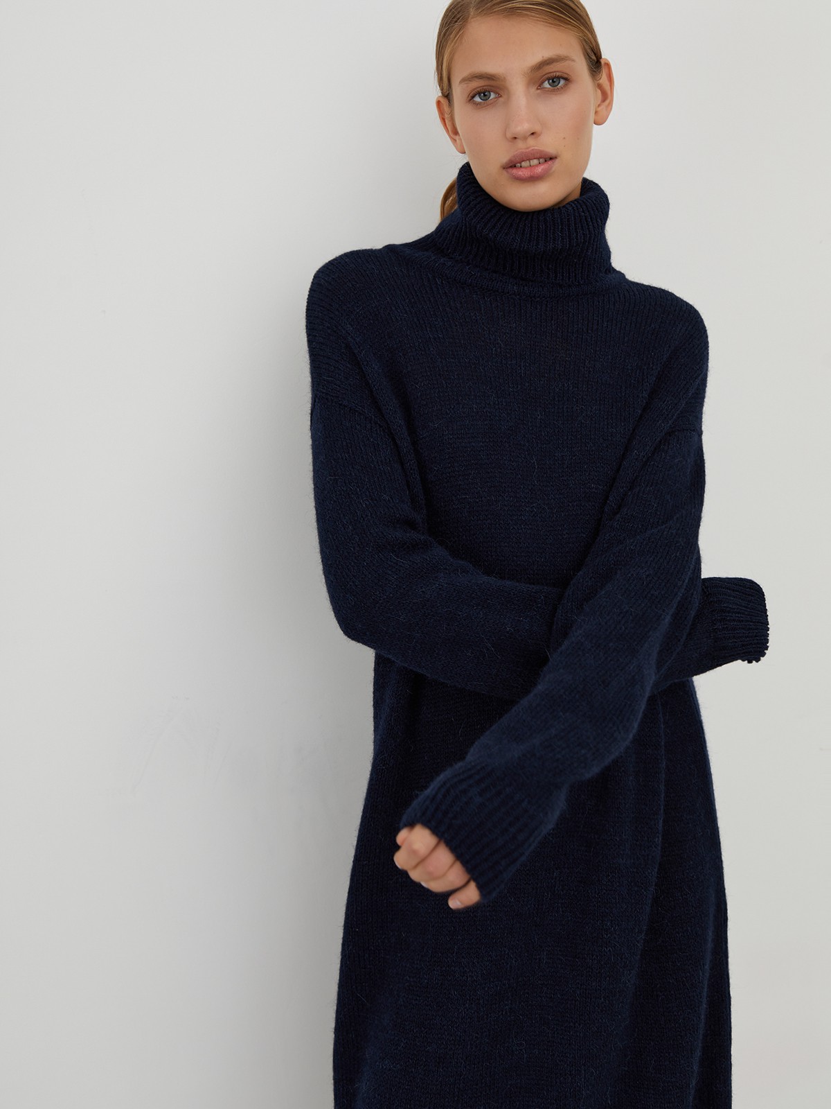 Трикотажное платье длины миди прямого кроя. Дополнено широким высоким воротом. По низу рукава и низу изделия притачан манжет, что создает удобство при ношении платья. Идеальный вариант для прохладных зимнихпрогулок и уютных посиделок с друзьями.