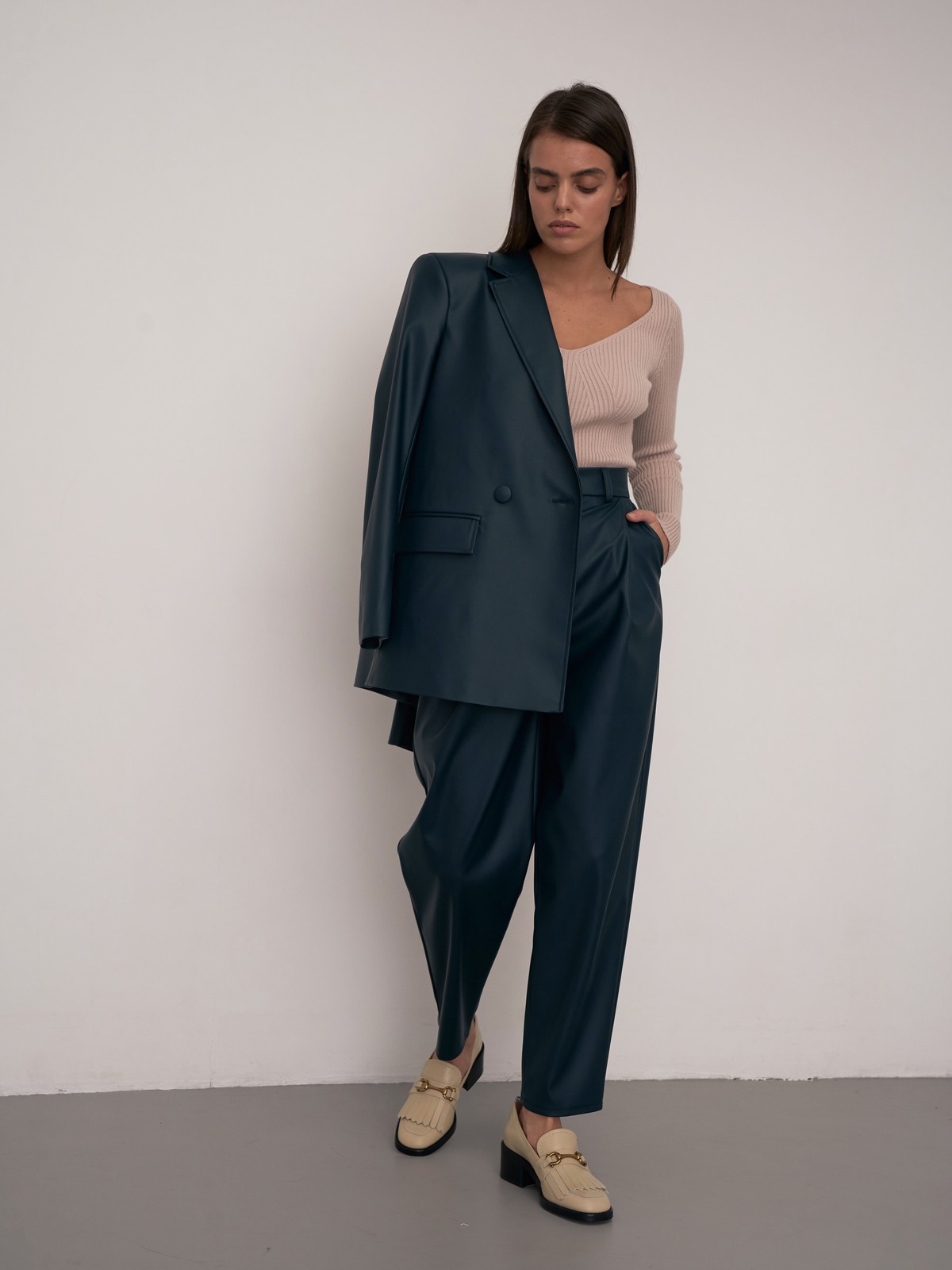 Жакет двубортного кроя выполнен из эко-кожи и оформлен заостренными лацканами, акцентированной плечевой линией и карманными клапанами по бокам.

На модели размер XS