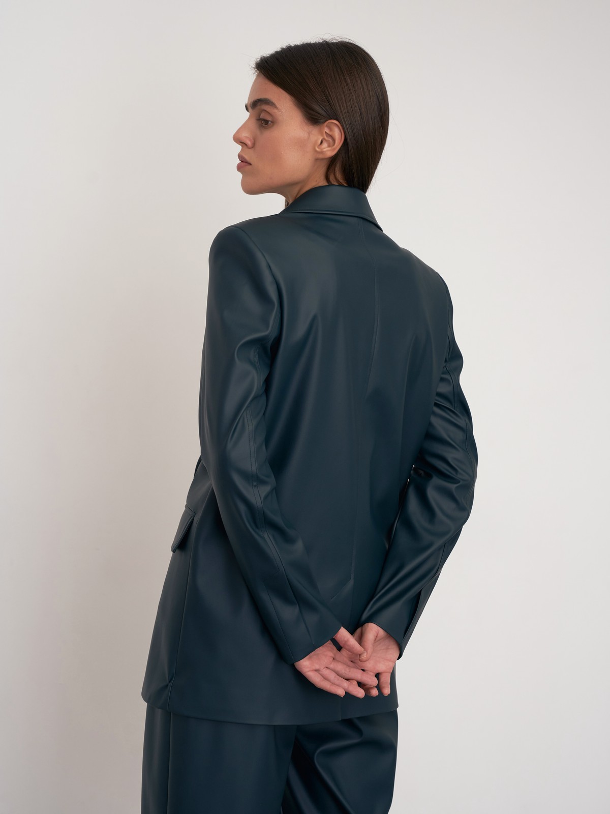 Жакет двубортного кроя выполнен из эко-кожи и оформлен заостренными лацканами, акцентированной плечевой линией и карманными клапанами по бокам.

На модели размер XS