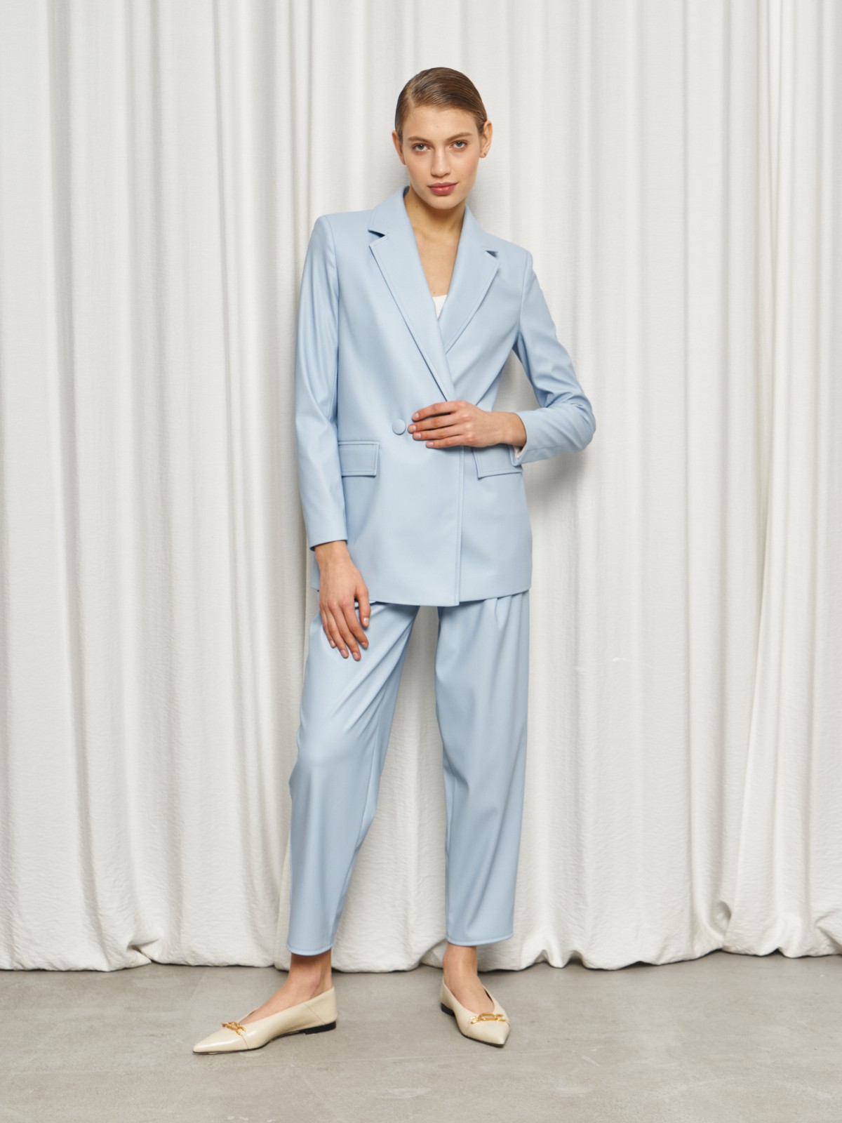 Жакет двубортного кроя выполнен из эко-кожи и оформлен заостренными лацканами, акцентированной плечевой линией и карманными клапанами по бокам.

На модели размер XS